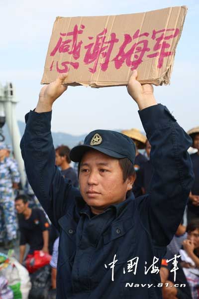 上圖為我官兵把作訓(xùn)服贈(zèng)送給獲救漁民穿